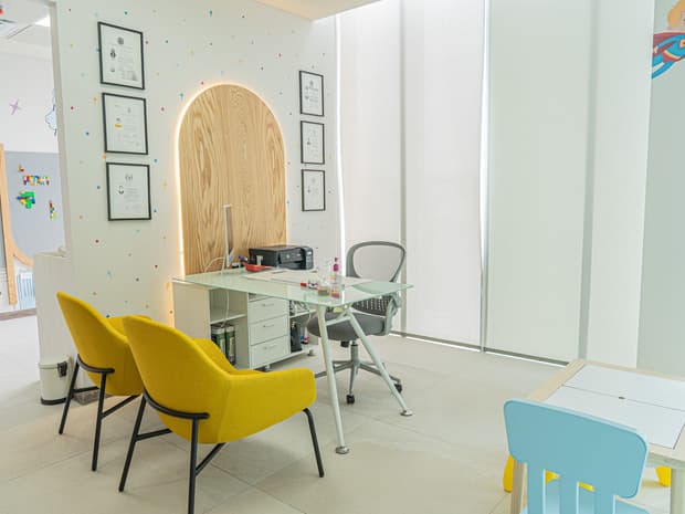 Sala de espera del consultorio con sillones amarillos y un arco de madera al fondo.