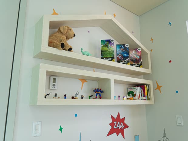 Repisas con juguetes, libros y figuras, decoradas con estrellas y cometas.