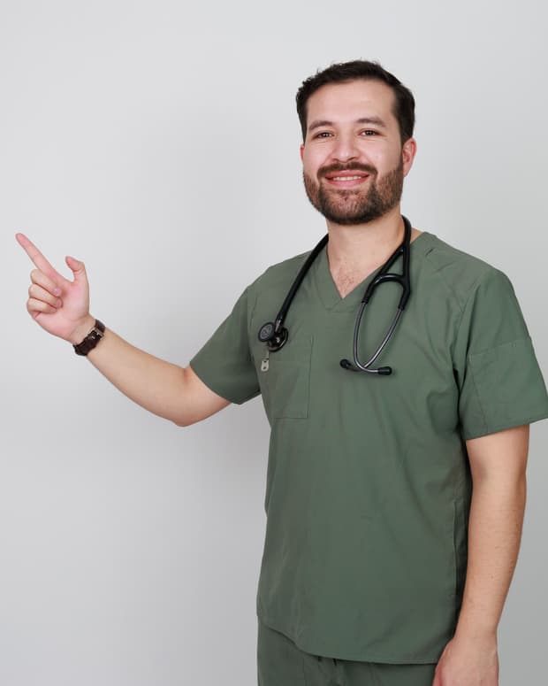 El Dr. Ramsés Zúñiga en uniforme quirúrgico con estetoscopio, señalando hacia un lado.